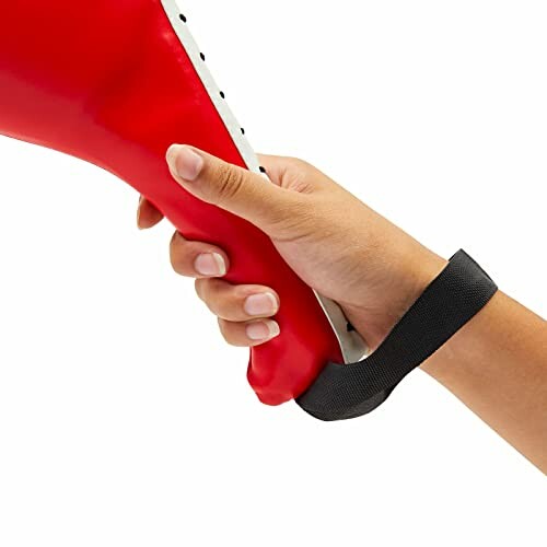 Hand holding a red punching pad with a black strap.