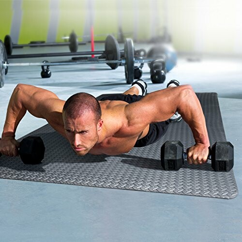 Man performing push-up with dumbbells in gym.